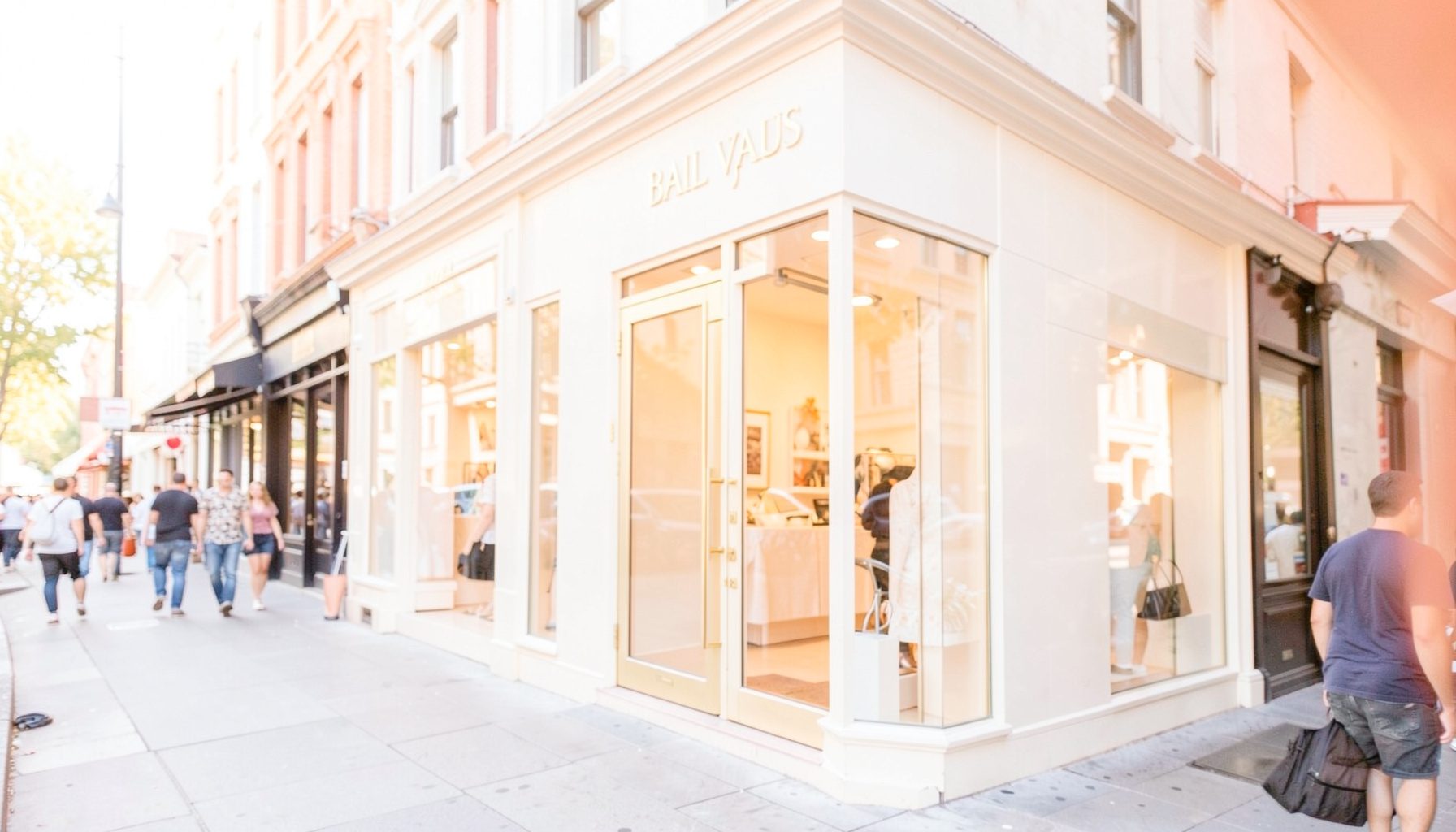 Elegant storefront with large glass windows and subtle gold signage, set along a bustling city street under soft afternoon light.