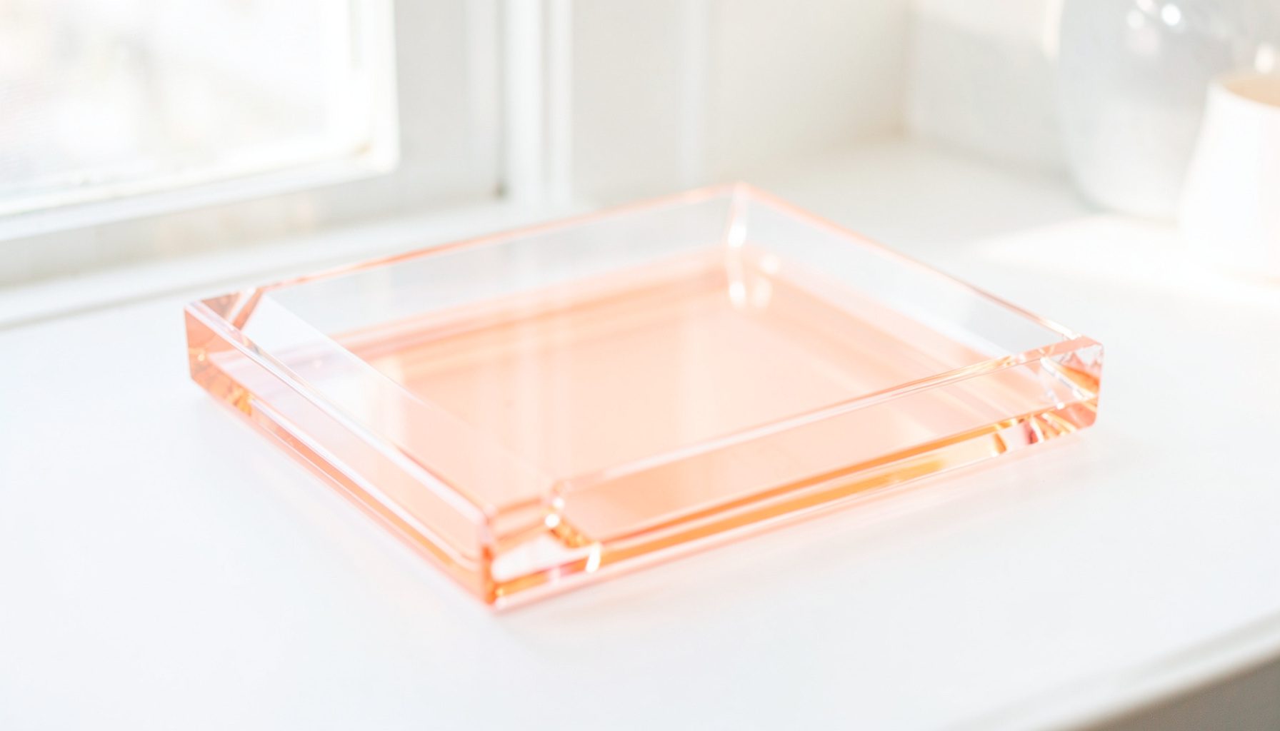 A crystal-clear acrylic picture tray with beveled edges, displayed on a bright windowsill with soft daylight