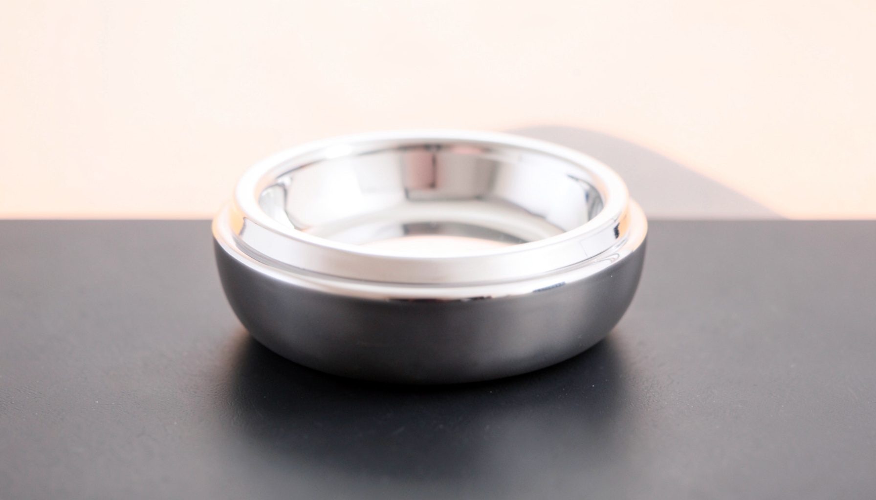 A polished silver-plated ashtray with a smooth, weighty form, resting on a dark matte surface