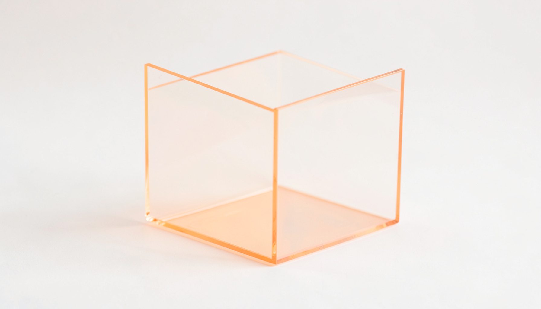 A sleek transparent acrylic paper bin with clean geometric lines, photographed against a soft neutral backdrop